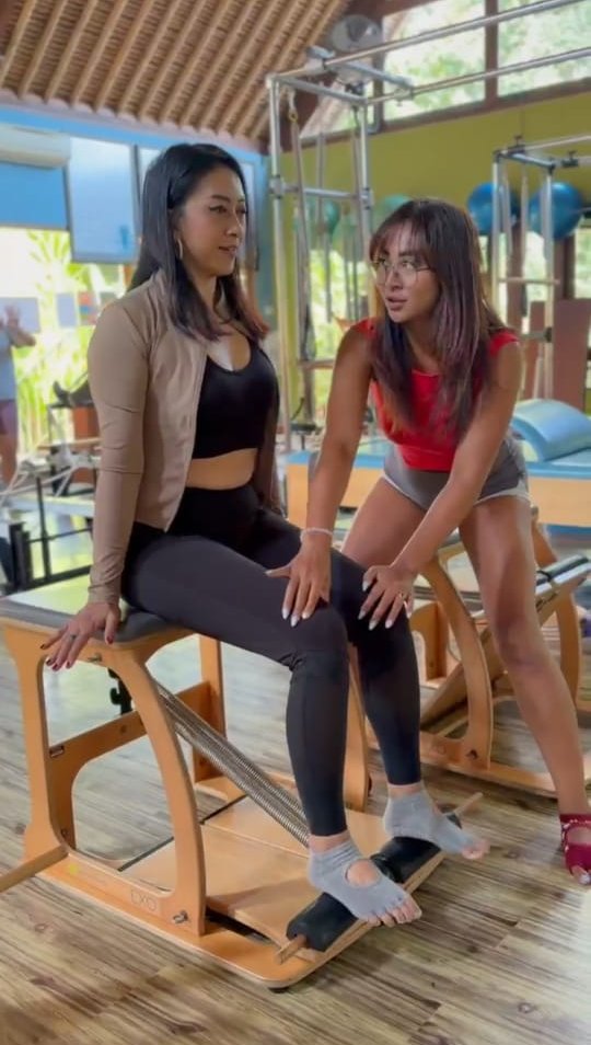 Nana correcting a client's alignment on the Pilates chair