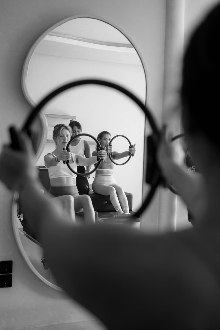 Two women working with Pilates rings, reflected in a mirror